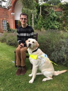 Photo shows a photo of me and Guide Dog Blossom sitting in a house garden posing for a photo. Blossom is wear her Guide Dog harness.
