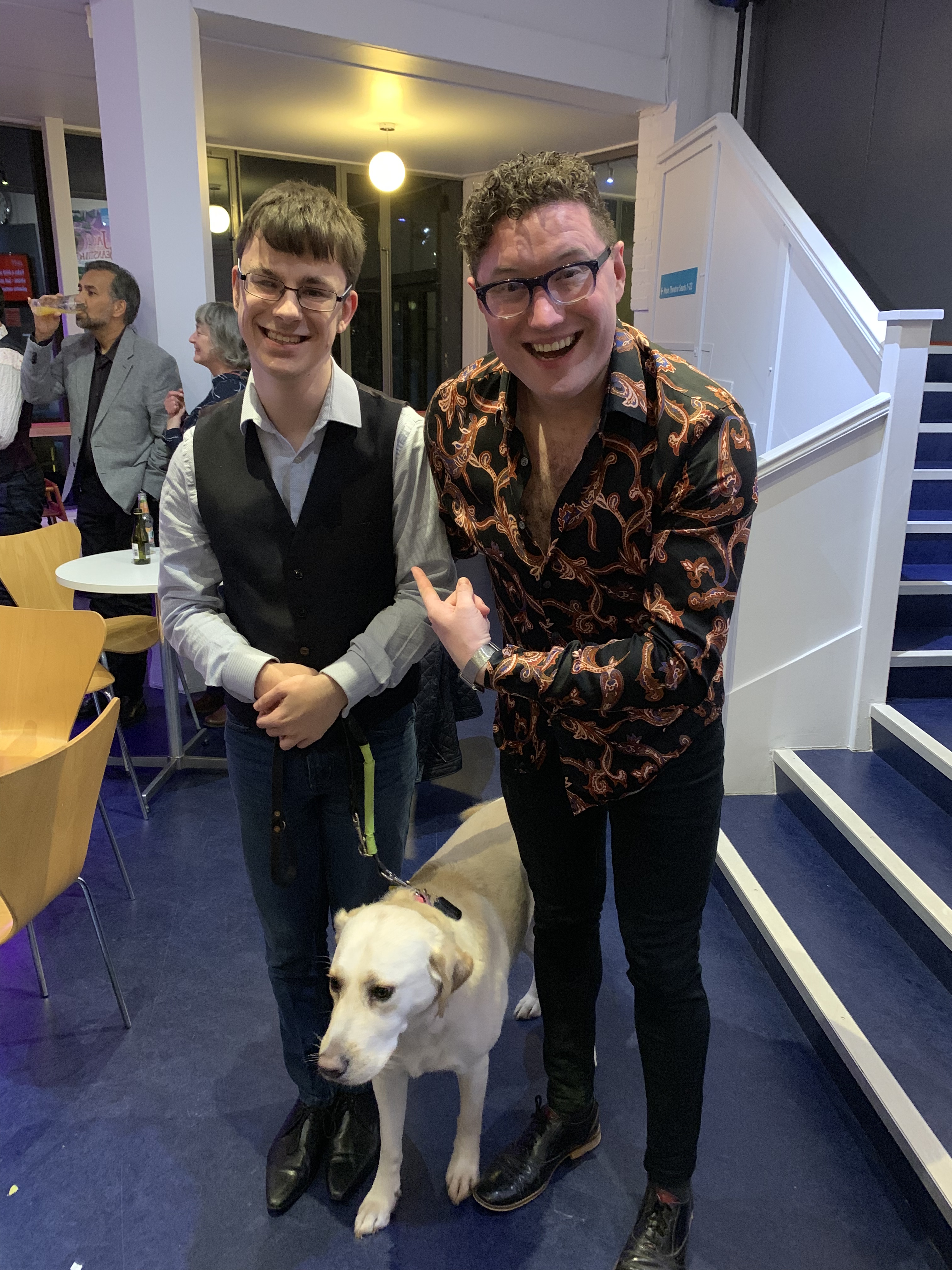 photo shows me and Antony-Stuart-Hicks after the show at the press party. Both me and antony are standing next to each other, with Guide Dog Blossom in the middle. Anthony is smiling very excitedly whilst pointing at me!