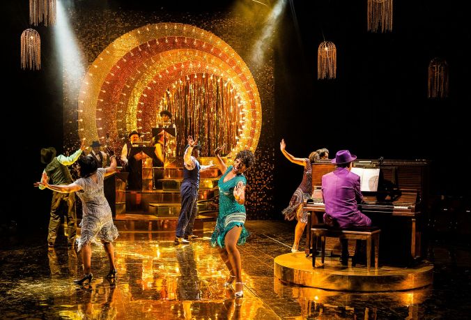 photo shows all the cast dancing and singing with a full band and piano playing the background