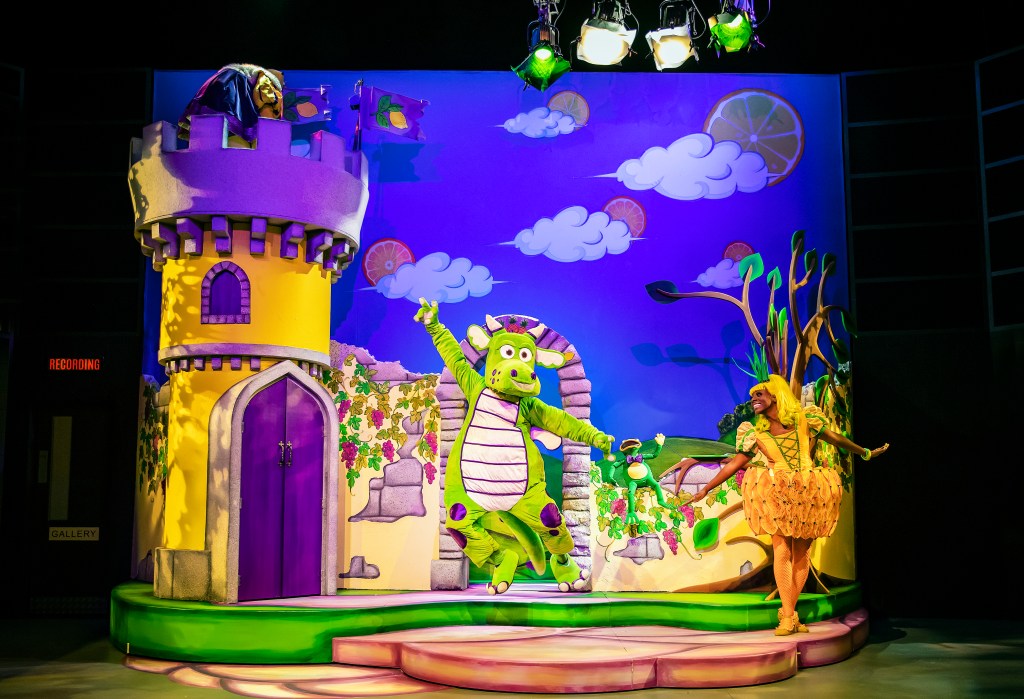 a full shot of the whole set with the dragon dancing and jumping also with princess pineapple with bright lights all around them.