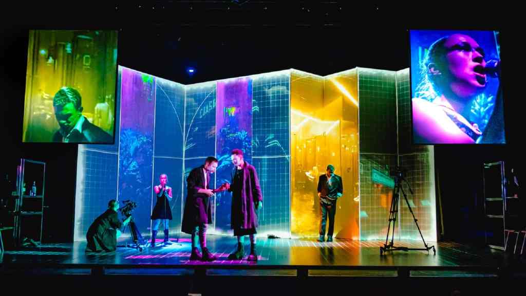 Various colours on all the screens with two of the clowns talking to each other, while lady macbeth is signing into a microphone.