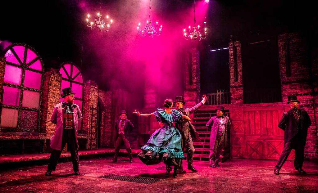 Photo shows Pip and Estella dancing in front of a crowd in a very pink lighting
